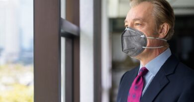 Mature businessman thinking and looking outside the window with mask for protection from corona virus outbreak